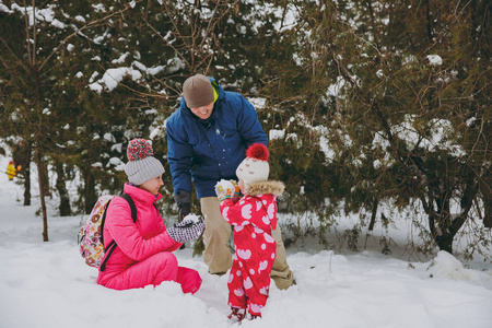 幸福的家庭女人男人和小女孩在冬天温暖的衣服玩耍，在雪地公园或森林户外做雪球。 假日的冬季乐趣休闲。 家庭生活方式观念