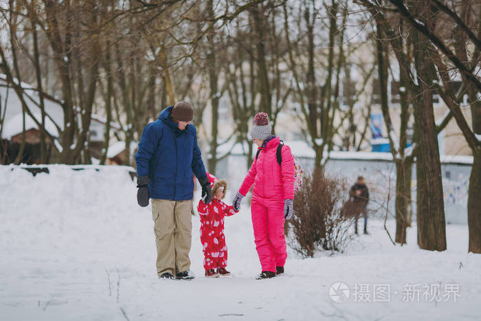 年轻的家庭妇女,男人和小女孩穿着冬天温暖的衣服,在雪地公园或森林