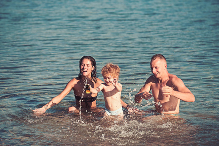 孩子与父亲和母亲。孩子在水中玩耍与父母