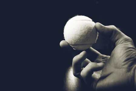 孩子的手在浅色的背景下挤压黄色的绿色网球.照片