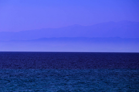 海水背景雾山背景。 蓝色的海洋平静的波浪表面背景山的背景。