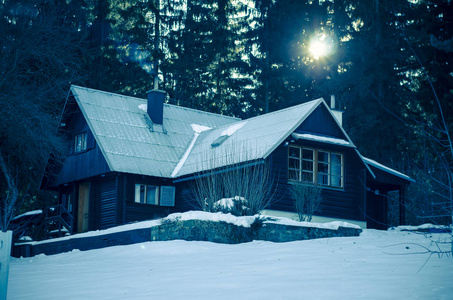 冬天的风景，有浪漫的小屋，烟囱里冒出烟雾，树林间有明亮的冬日阳光