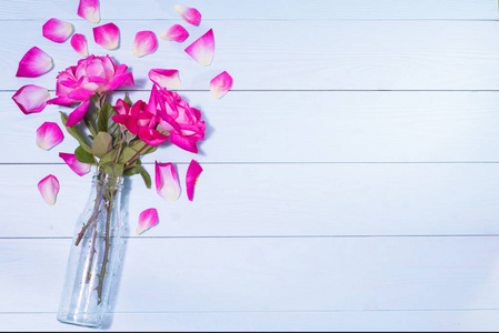 蓝色木制背景上花瓶里的粉红色玫瑰。 贺卡概念。 结婚邀请。