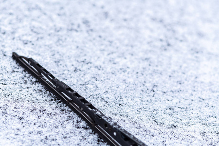 雪覆盖的车窗与雨刷宏观关闭。 防冻液没有使用。 雪地里的车辆。 冬天的时间来了。 恶劣天气条件