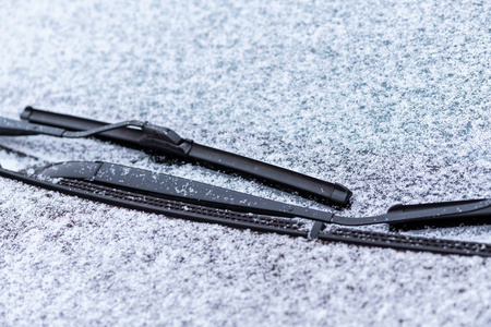 雪覆盖的车窗与雨刷宏观关闭。 防冻液没有使用。 雪地里的车辆。 冬天的时间来了。 恶劣天气条件