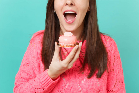 裁剪形象的年轻女孩穿着针织粉红色毛衣，手拿着吃蛋糕，孤立在蓝色绿松石墙背景工作室肖像上。 人们真诚的情感生活方式观念。 模拟复制