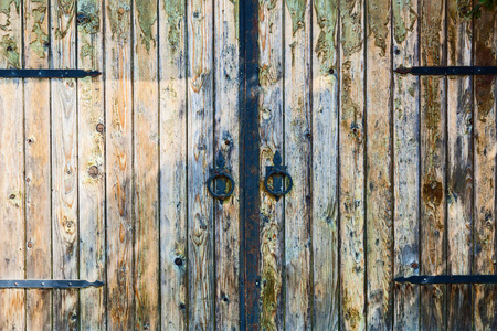 旧木门，有锻造的圆形旋钮，挂在锻造的铰链上