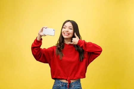 微笑的年轻女孩在智能手机上的自拍照片在黄色背景