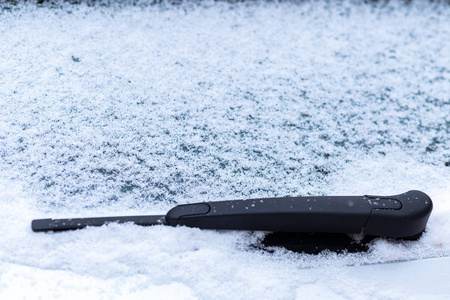 雪覆盖的车窗与雨刷宏观关闭。 防冻液没有使用。 雪地里的车辆。 冬天的时间来了。 恶劣天气条件