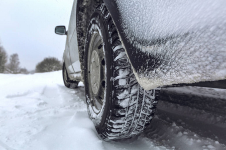 视图集中在汽车轮胎和后保险杠上的冬季道路覆盖着雪。降雪后在雪路上行驶的车辆