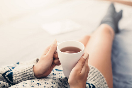 妇女休息在床上与一杯茶