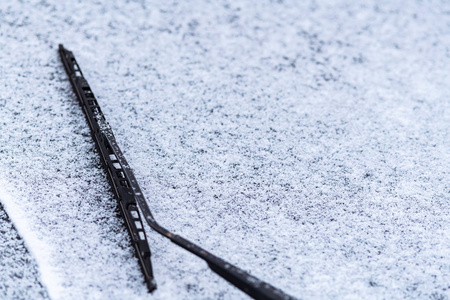 雪覆盖的车窗与雨刷宏观关闭。 防冻液没有使用。 雪地里的车辆。 冬天的时间来了。 恶劣天气条件