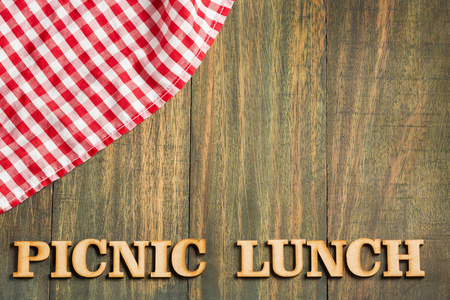 野餐午餐木制背景与格子餐巾。 木头上的字母