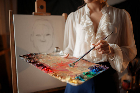 女画家与调色板和刷子站在画架在工作室。 创意绘画女人画铅笔素描车间内部背景