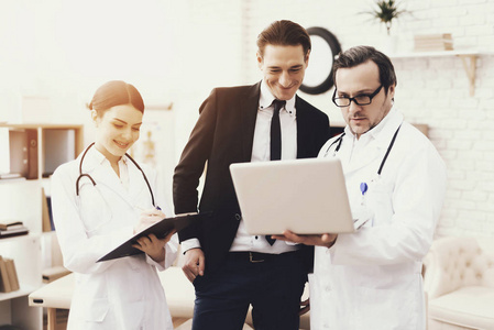 有经验的医生在笔记本电脑上展示成功商人的体检结果
