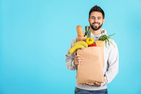 男人拿着纸袋，在彩色背景空间上有新鲜产品供文字使用。 食物供应服务