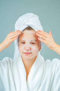 面部护理和美容治疗。美丽的女人，脸上戴着一张保湿面膜。化妆程序。