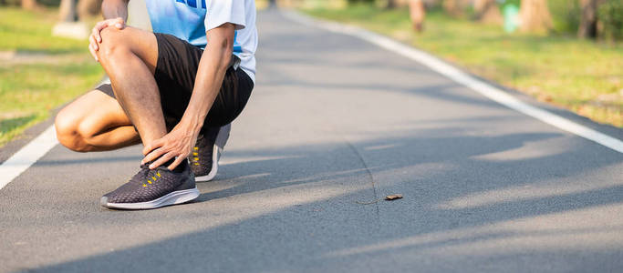 年轻的健身男子抱着他的运动腿受伤。训练过程中肌肉疼痛。亚洲跑步者在早上跑步和运动后脚踝疼痛和问题。运动和健康概念