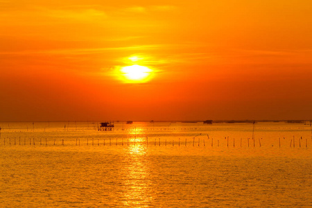 海滩上的日落，太阳从云层和海洋中反射出来。