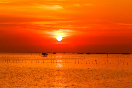 海滩上的日落，太阳从云层和海洋中反射出来。