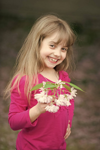 用微笑面对抱着粉红色的樱花绽放的小宝贝女儿