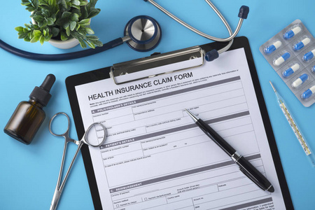 健康保险表格和笔放在医生桌上，蓝色背景