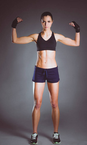 肌肉构成的运动服在黑色背景下的年轻女子