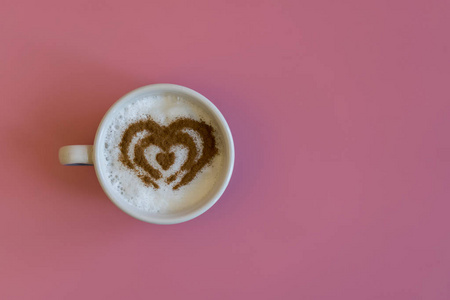 粉红色背景下咖啡杯中的心形装饰。