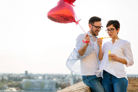 在情人节那天，一对微笑的情侣在日落时爱上了气球