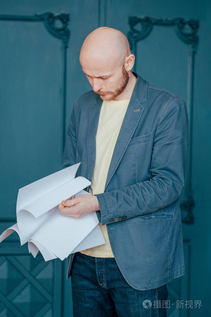 一个穿着蓝色夹克西装,手里拿着一张纸的秃头男人