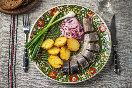 鲱鱼与烤土豆和洋葱在亚麻桌布上的花纹乡村版