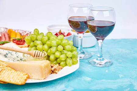 意大利反帕斯蒂葡萄酒小吃一套。 反胃餐饮盘与肉干萨拉米奶酪葡萄橄榄泡菜甜瓜胸罩蓝色背景。 意大利食品配料。 地中海