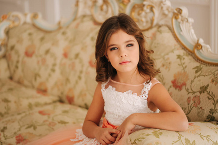 小女孩的肖像。美丽的眼睛的模型。小公主坐在沙发上