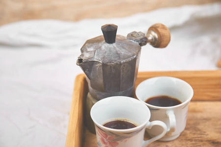 莫卡咖啡壶，两杯咖啡在白色背景的木制托盘上。 老式意大利咖啡，柔和的复古色调。 复制空间
