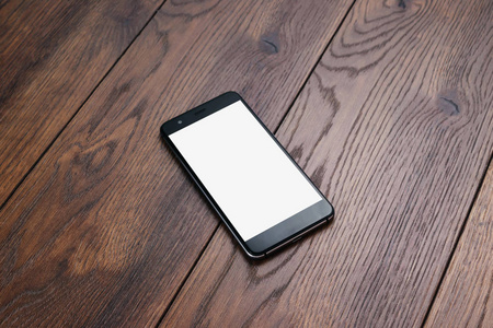 创意背景智能手机与白色屏幕的背景木桌模型。 设计移动应用手机游戏技术的准备概念。