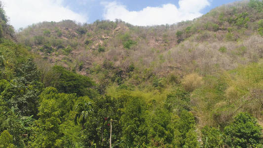 鸟瞰山坡，群山覆盖着森林和植被，映衬着蓝天。 亚洲山地丘陵景观。 热带景观