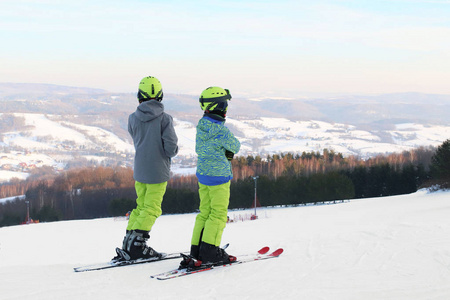 两个滑雪者站在白雪覆盖的山脉上，准备一个回转坡道。 冬季运动的现代体育设备。 采矿胜地。 露天的体育活动。 面对审判。