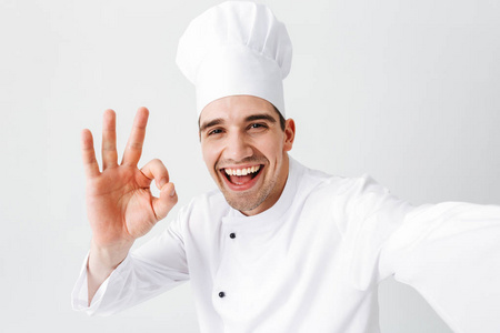 快乐的厨师穿着制服，站在白色背景上，自拍，表现得很好