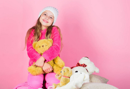 孩子小女孩玩软玩具泰迪熊粉红色的背景。填充动物的独特附件。小女孩顽皮地拿着泰迪熊毛绒玩具。泰迪熊改善心理健康