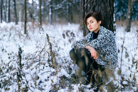 寂寞的女孩坐在冬天的雪林里