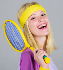 网球俱乐部的概念。女孩可爱的金发碧眼打网球。运动为维护健康而运动。运动员手拿网球拍在灰色背景。积极的休闲和爱好。网球运动和娱乐