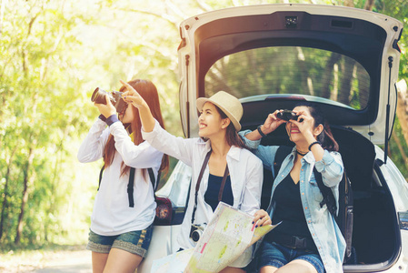 旅行团亚洲女旅行者坐在掀背车上，在假期和假日旅行中与户外森林一起旅行。 旅行概念