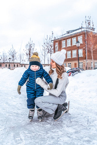 一个46 的小男孩正在滑冰。快乐的微笑, 妈妈让她的儿子帮助留下。溜冰鞋的第一步。冬天在溜冰场上的城市