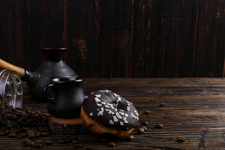 甜甜圈与黑色糖霜和巧克力粉和一杯正宗的浓咖啡。 一罐咖啡豆和倒谷物。