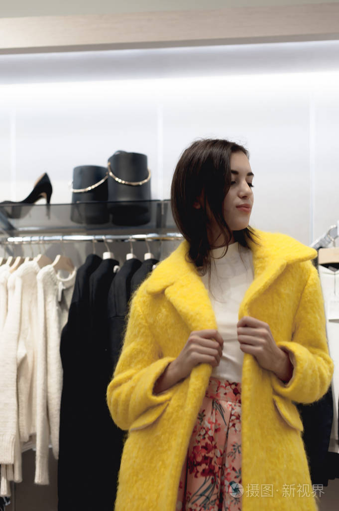 年轻,美丽,情绪化的现代女性走过购物中心,看看服装店里的时装