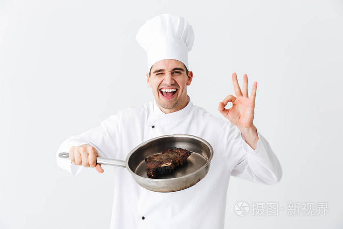 欢快的厨师穿着制服，煎锅与熟牛排隔在白色背景调料上
