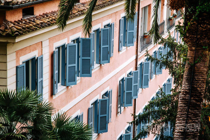 带有木制百叶窗的欧式窗户. 房子的外部被棕榈树包围.