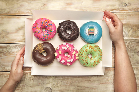 s hands hold box with different donuts