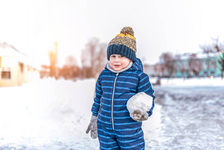 一个36 的小男孩冬天站在外面的城市里。手里拿着一个大雪球。文本的可用空间。冬季的儿童游戏