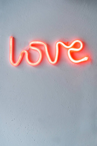 白色墙上的红色霓虹灯爱情标志。 选择性聚焦。